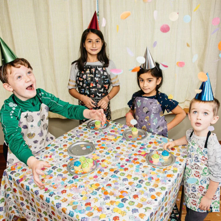 Children at a birthday party with colorful tablecloth and confetti.