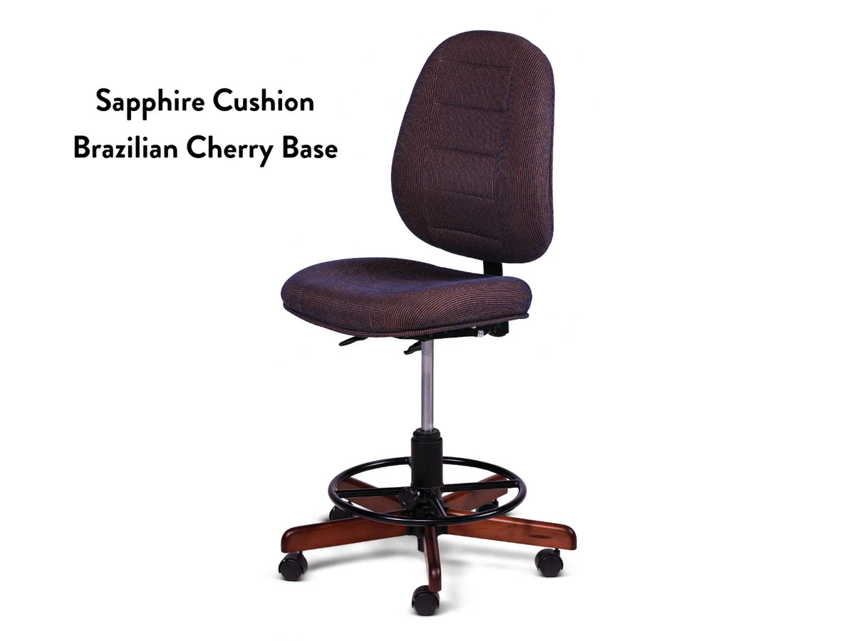 The Koala SewComfort Chair features a blue Sapphire Cushion, ergonomic design, round footrest, and a Brazilian Cherry wooden base on wheels. Text on the left reads: Sapphire Cushion Brazilian Cherry Base.