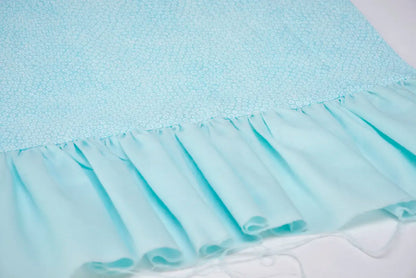 Light blue fabric with a small circular pattern and a sheer, ruffled edge shows loose threads along the seam, which could be easily finished using the Baby Lock Celebrate Serger Machine’s Jet-Air Threading feature.