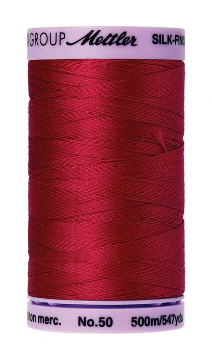 A spool of Mettler Cotton Silk Finish 50wt thread in Country Red, 500m/547yds, is shown against a white background.