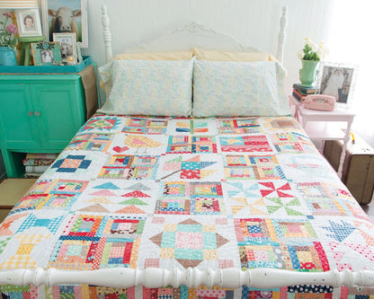 A bed adorned with colorful quilts, featuring charming patterns from Checker Distributor’s Farm Girl Vintage collection.