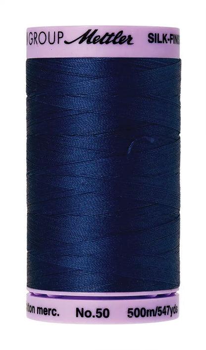 A spool of Mettler Cotton Silk Finish 50wt 500m in Imperial Blue with pink ends—ideal as a high-quality quilting thread.