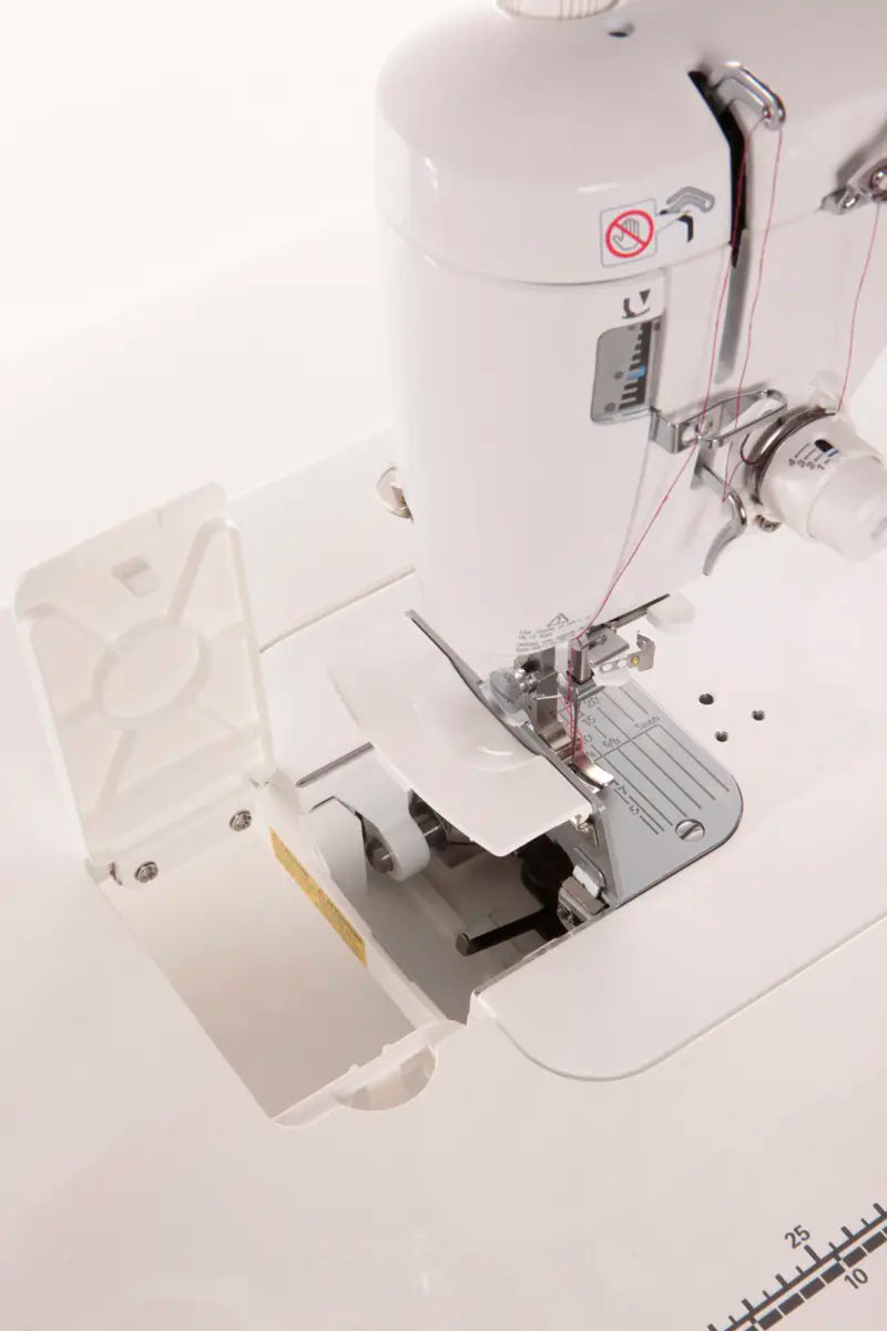 Close-up of the JUKI TL-2000Qi Sewing and Quilting Machine with its bobbin case compartment open, revealing the inner mechanism and thread guides against a plain white background.