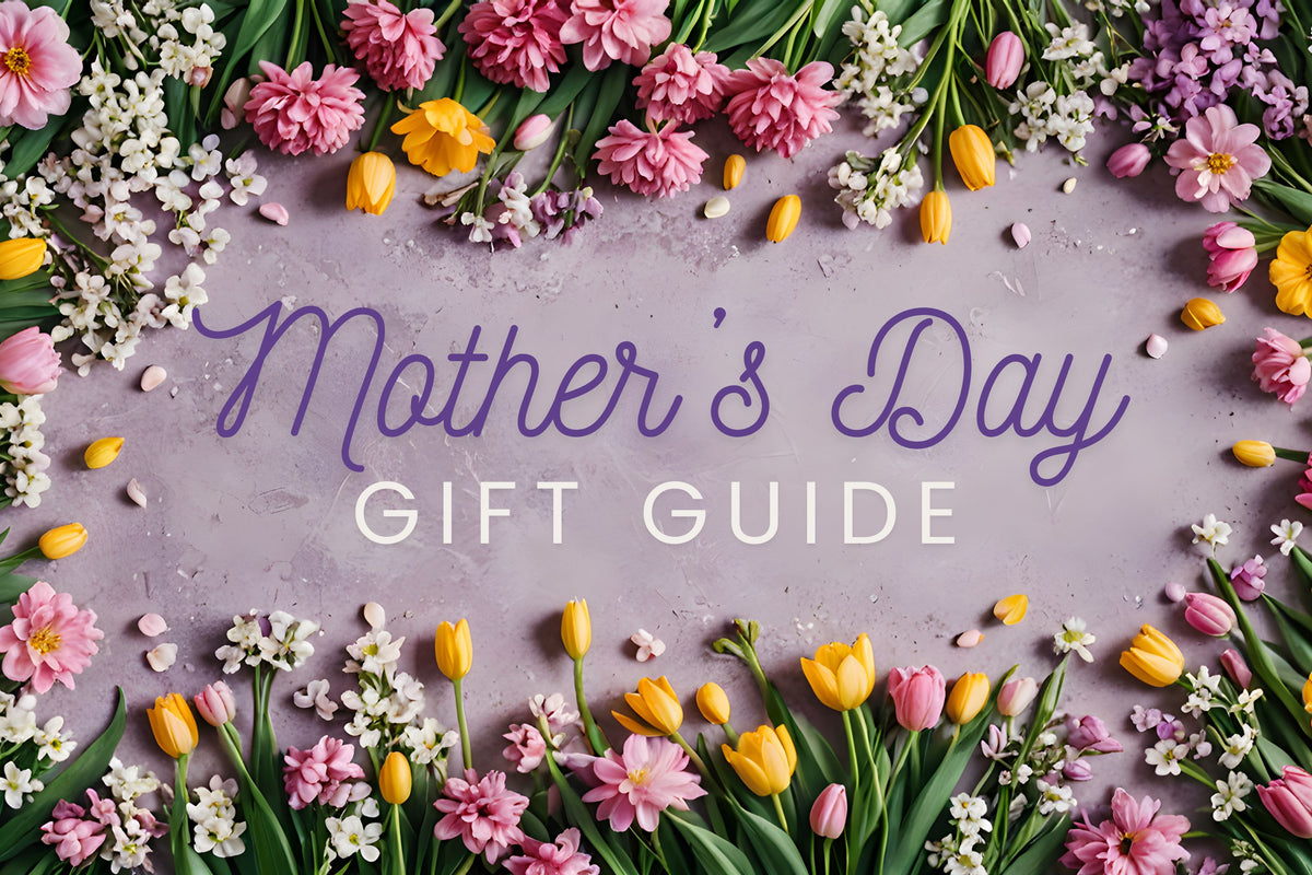 A pastel purple background with “Mother’s Day Gift Guide” written in the center, surrounded by colorful flowers including tulips, daisies, and small white blossoms.