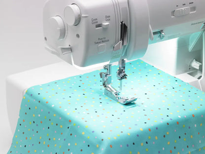 A close-up of a Baby Lock Triumph Serger Machine stitching light blue polka dot fabric, highlighting the needle area—perfect inspiration for free online classes or learning RevolutionAir threading.