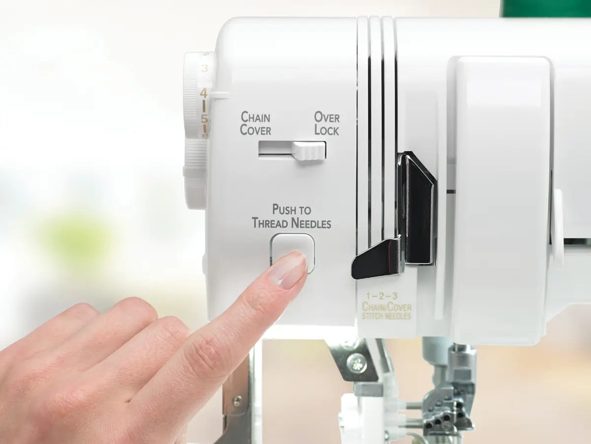 A close-up of a hand pressing the Push to Thread Needles button on the Baby Lock Triumph Serger Machine, highlighting its RevolutionAir threading feature and showing various controls and labels on the machine's white surface.