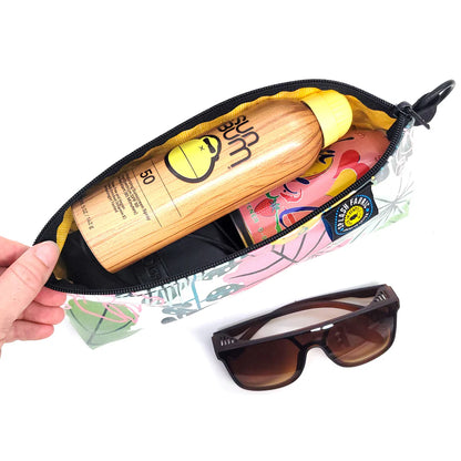 Open pouch with sunscreen, sunglasses, and other items on a white background