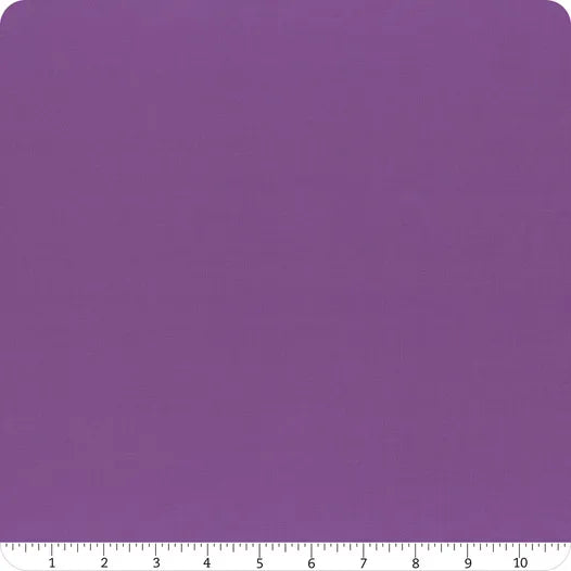 A square piece of Riley Blake Confetti Cotton™ Iris Solid Fabric Yardage with slightly rounded corners is shown, with a ruler along the bottom edge displaying measurements from 0 to 12 inches.
