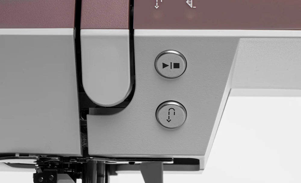 Close-up of two metallic buttons on the Pfaff Quilt Ambition 635 Sewing and Quilting Machine by Quilted Joy, featuring a triangle and a curved arrow symbol, both near the stitching area with Integrated Dual Feed Technology.