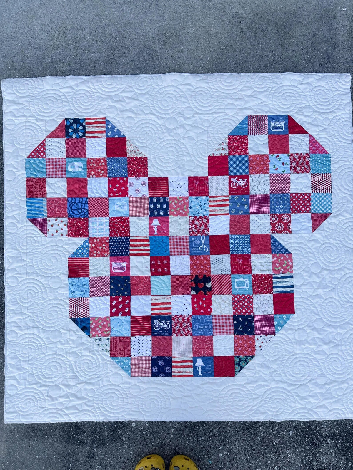 Patchwork quilt with a bear design on a concrete floor