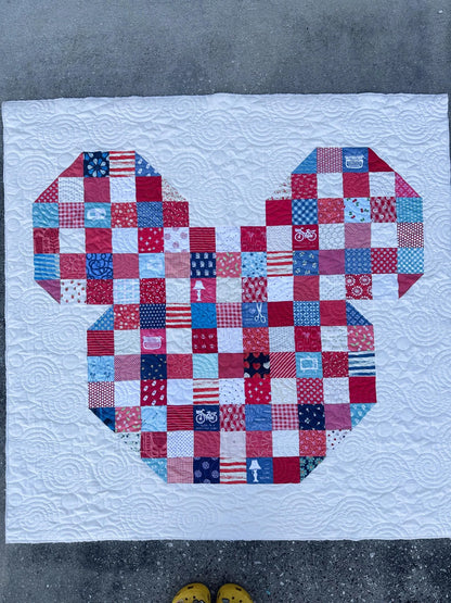 Patchwork quilt with a bear design on a concrete floor