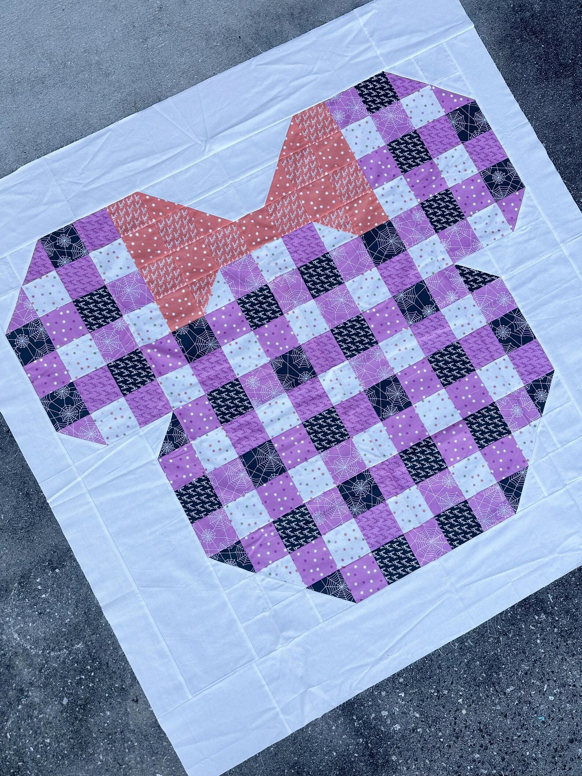 Quilt with a purple and black checkered pattern on a gray surface