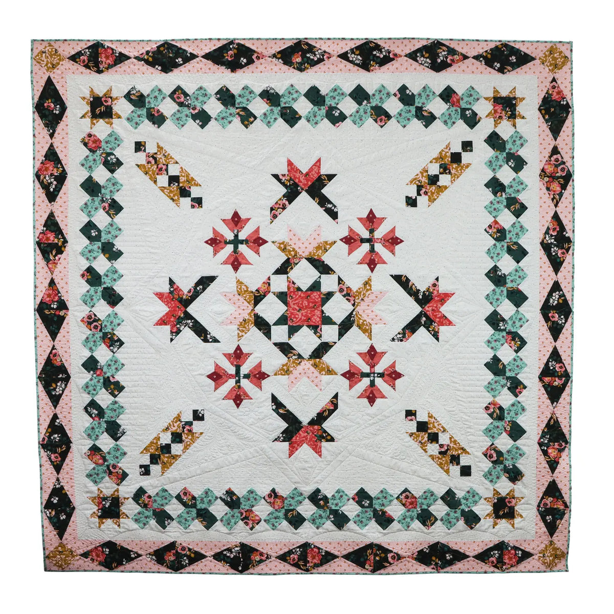 A handmade quilt with a white background, featuring geometric and floral patterns in red, green, black, gold, and pink, arranged in symmetrical rows with a decorative multicolored border.